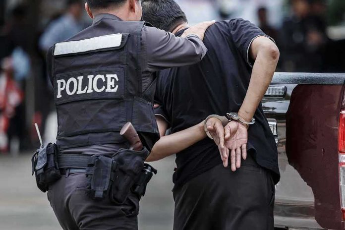 shutterstock_693957643 Police officer escorting handcuffed man to a vehicle