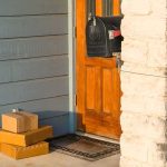 Packages stacked on a doorstep by a wooden front door