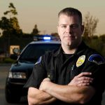 Candidate Sex Offender ARRESTED – Committed Worse Offense! Police officer standing with arms crossed in front of patrol car