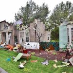 Houses with significant storm damage and debris scattered around the yard