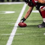 football player setting the ball on the line of scrimmage