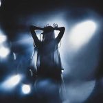 Silhouetted singer on stage amid dramatic blue spotlights