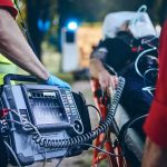 Paramedic with defibrillator beside patient on stretcher