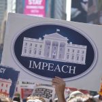 Protest crowd holding an impeach sign with the White House emblem
