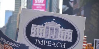 26-Count Impeachment Blitz Hits Trump Protest crowd holding an impeach sign with the White House emblem