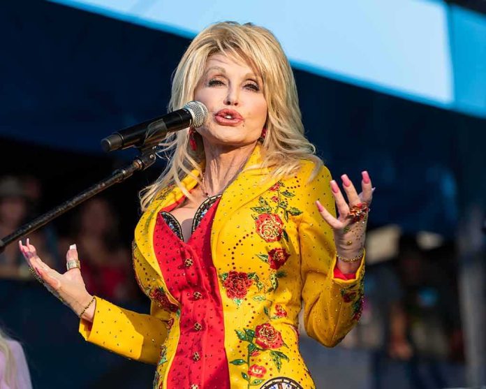 shutterstock_1596680992 Dolly Parton performing on stage in a yellow floral jacket