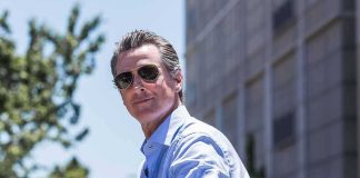 man in sunglasses wearing a light blue shirt outdoors