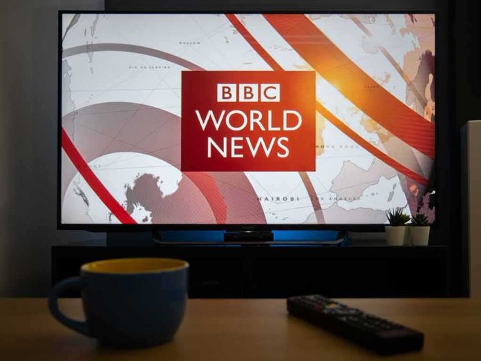 Television displaying world news program with cup and remote in foreground
