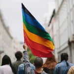 Person holding a rainbow flag in a city street march