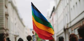 162 LQBTQ Arrested in Midnight Raid Person holding a rainbow flag in a city street march