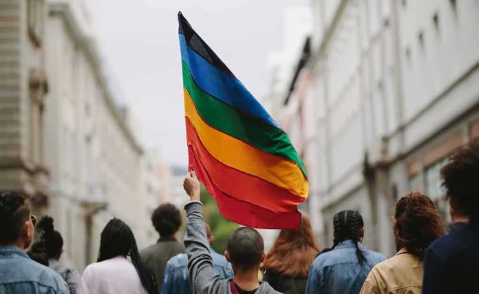 shutterstock_1736459822 Person holding a rainbow flag in a city street march