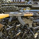Assorted firearms and ammunition laid out in a dense pile