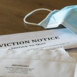 Eviction notice and torn envelope beside blue surgical masks