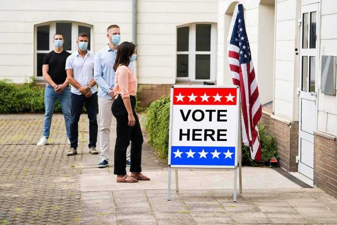 shutterstock_1772910065-1 Voters wearing masks line up outside a polling place