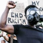 Protester in gas mask raising fist at a rally