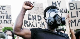 Protester in gas mask raising fist at a rally