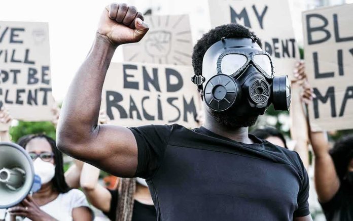 shutterstock_1793905738 Protester in gas mask raising fist at a rally