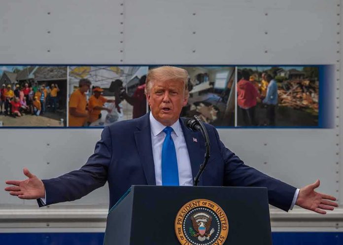 shutterstock_1804636972 Donald Trump speaks at a podium with arms outstretched