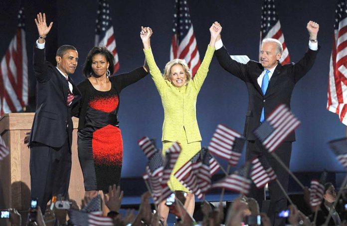 Barack Obama, Michelle Obama, Jill Biden, and Joe Biden celebrate on stage with U.S. flags
