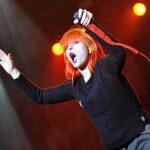 Singer with bright orange hair performing on stage