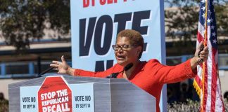 L.A. Homeless Empire Frozen – Bass in the Super Hot Seat Speaker at outdoor rally behind podium with vote signs