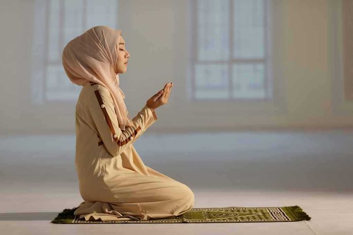Woman in hijab praying on a mat indoors