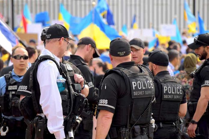shutterstock_2132863557 Police officers stand among a crowd with blue and yellow flags