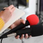 Bomb Squad FINDS Grenade at Major Water Dam! Journalist holding two microphones while writing in a notebook