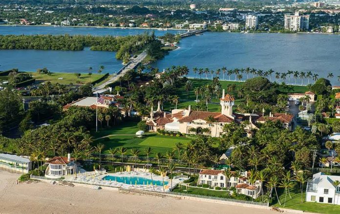 Aerial view of a waterfront estate with pool, lawns, and palm trees