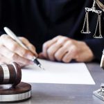 Surgeon Caught in Shocking Abortion Scandal Judge writing at desk with gavel and Lady Justice statue