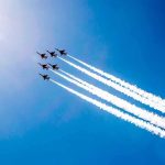 Six jet aircraft fly in formation leaving white smoke trails