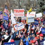 Tim Teufel, Christian Jones, and Nash the Slash among a crowd at a political rally holding signs and flags
