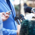NBA Star Torches Commie Mayor’s Arrogance Reporters hold microphones toward a person in a blue suit