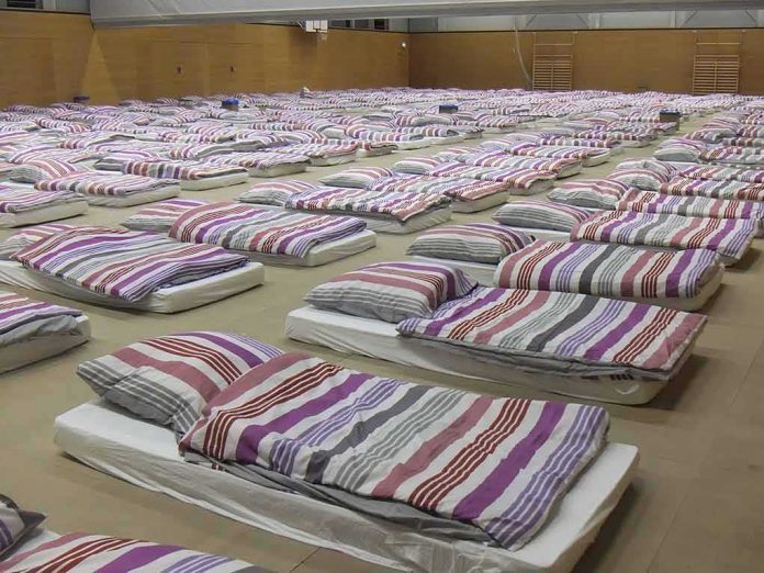 rows of mattresses with striped bedding in a large hall
