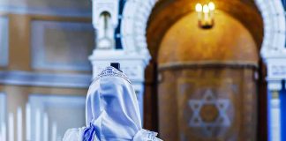 El-Sayed’s Lesbian Rosh Hashanah Plan BACKFIRES Spectacularly Person in white and blue prayer shawl facing ornate interior