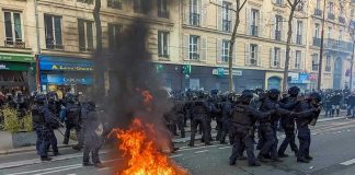 Fire burning on the street amid police presence.