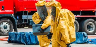 Toxic Leak Triggers Frantic Midnight Evacuation Hazmat workers in yellow suits carry equipment near a tanker truck