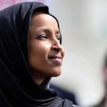 Ilhan Omar in profile wearing a black headscarf outdoors