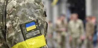 Soldier in camouflage with Ukrainian flag patch and yellow armband