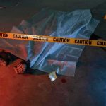 crime scene body under sheet behind caution tape