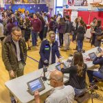 Don MacLean in a busy gymnasium voting station with check-in tables