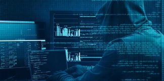 Hooded person at multiple computer screens with code and charts