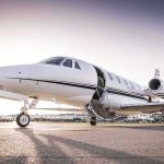 Private jet on airport tarmac with open door at sunset