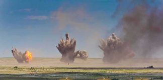 Multiple explosions erupt on a distant desert plain
